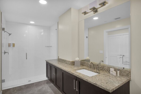 Un baño moderno con un espejo grande, un lavabo y una zona de ducha.