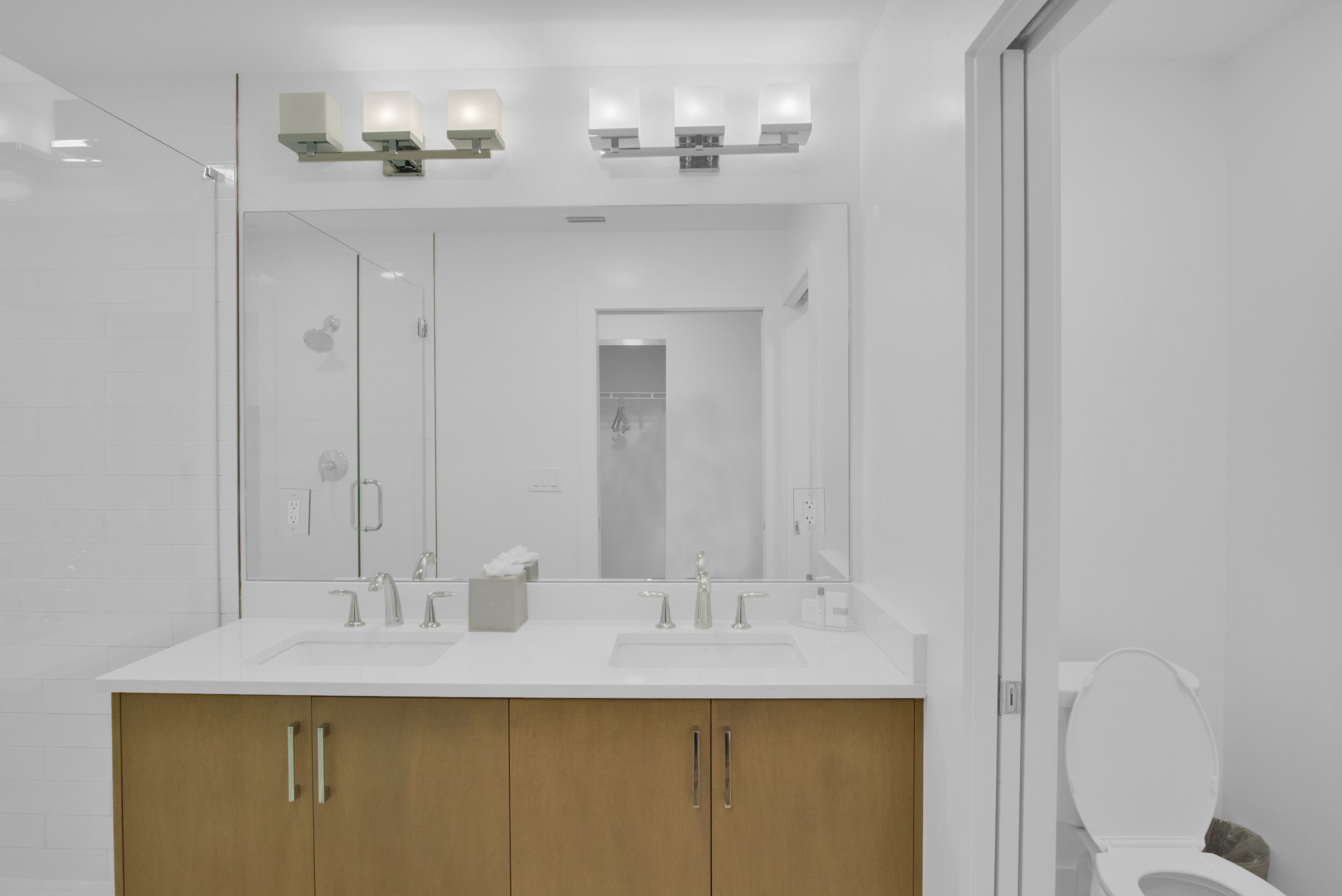 Une salle de bain moderne avec deux lavabos, un miroir et des toilettes.