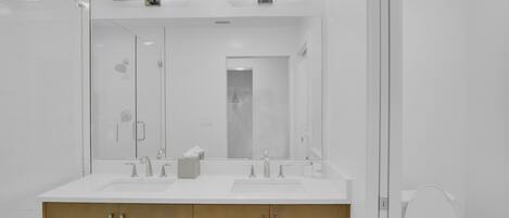 Une salle de bain moderne avec deux lavabos, un miroir et des toilettes.