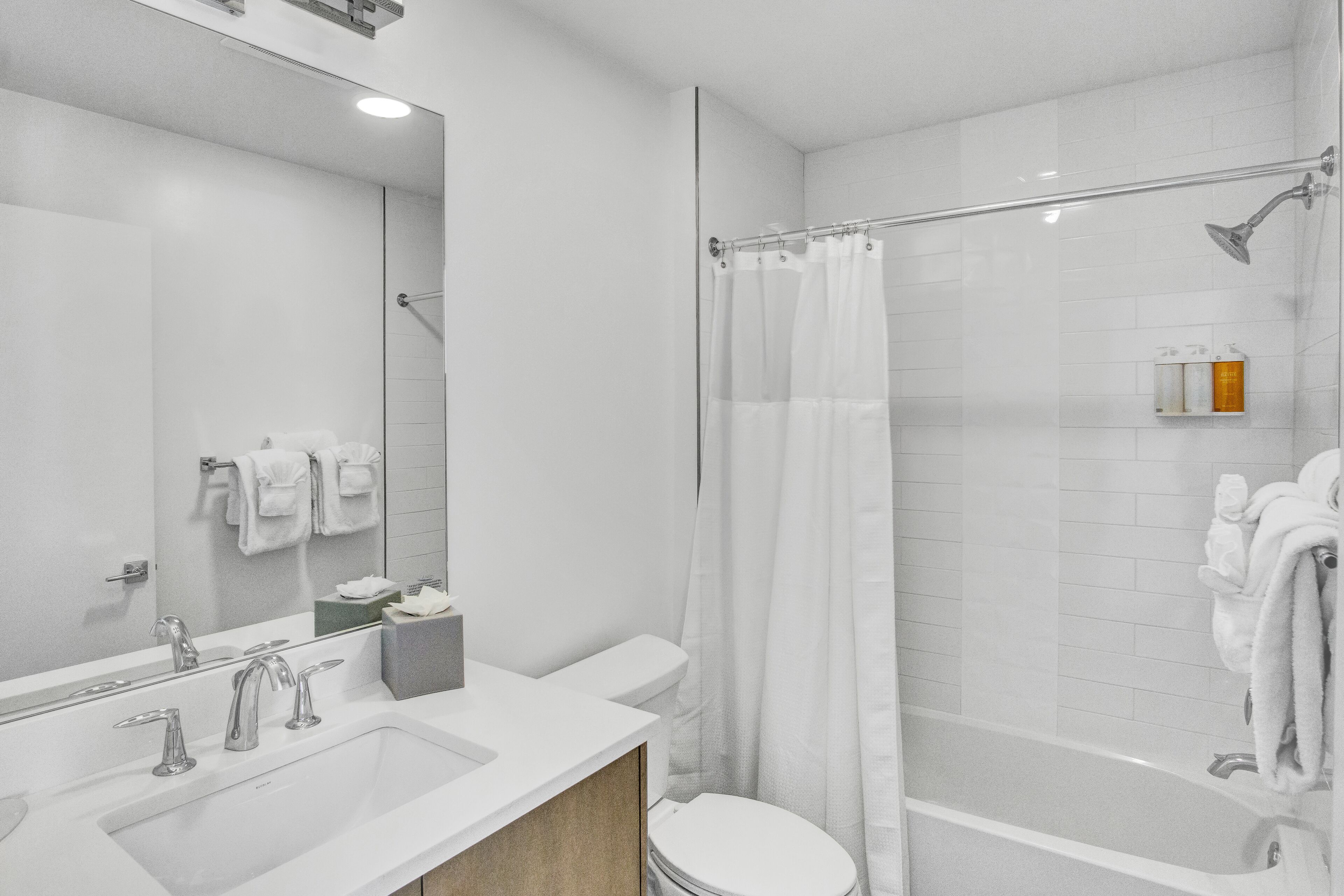 A modern bathroom with a large mirror, a sink, a toilet, and a shower area.