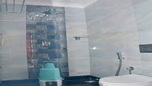 A modern bathroom with a large bathtub, a shower, and a small stool. - Anandha Grand (Tiruchendur)