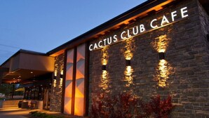 The exterior of the Cactus Club Cafe with illuminated signage and a stone facade. - D@home Entire &Family by Glenmore Reservoir/Heritage Park/ Rockview Hospital (Calgary)