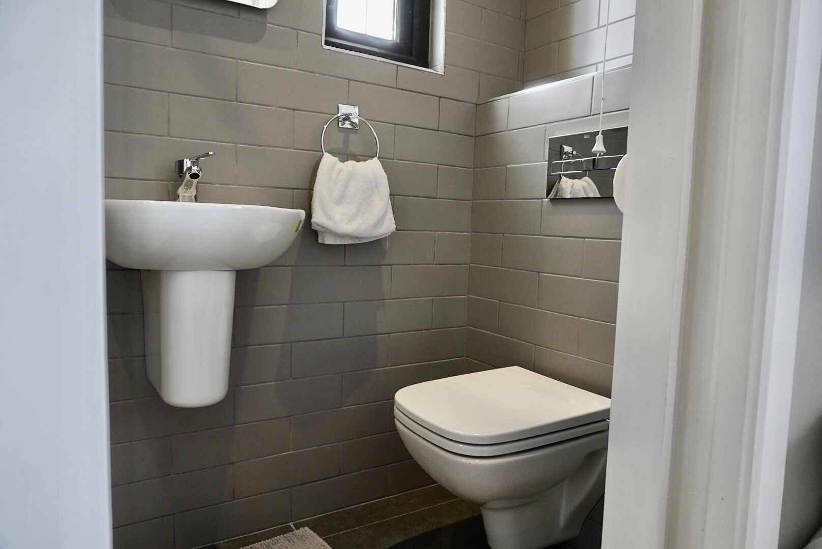 Et badeværelse med hvid vask, toilet og håndklædestang.