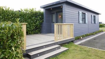 A modern single-story house with a wooden deck and a small porch.