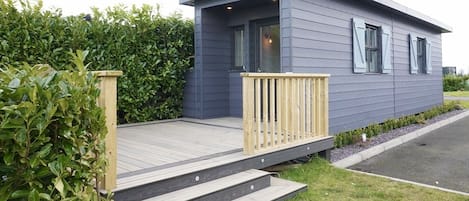 A modern single-story house with a wooden deck and a small porch.