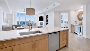 A modern kitchen with a large island, built-in appliances, and a view to the outside. - Turquoise Place C2605 | Gorgeous Updates! Oversized, hot tub/grill on deck, huge slide for kids! (Orange Beach)