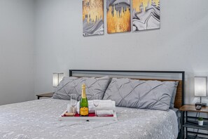Une chambre d’hôtel avec un lit, une table de chevet avec une lampe et des œuvres d’art accrochées au mur.