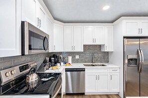 A modern kitchen with white cabinets, stainless steel appliances, a microwave, and a dishwasher.