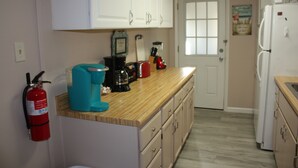 A kitchen with white cabinets, a wooden countertop, a coffee maker, a blender, and a refrigerator. - Cozy 1 Bedrm/1 Bth, Walk to Downtown, Pet Friendly, Fenced yard, Covered Patio (Prescott)