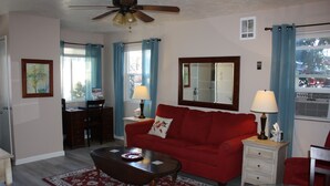 A living room with a red sofa, a coffee table, a glass table, and a ceiling fan. - Cozy 1 Bedrm/1 Bth, Walk to Downtown, Pet Friendly, Fenced yard, Covered Patio (Prescott)