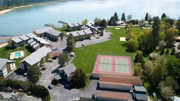An aerial view of a residential area with a tennis court, buildings, and a lake. - Downtown Sandpoint Lakeside Condo (Sandpoint)