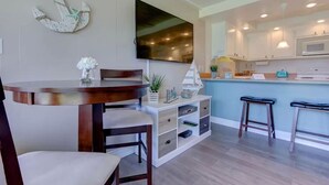 A dining area with a round table, chairs, and a small island with stools. - Downtown Sandpoint Lakeside Condo (Sandpoint)