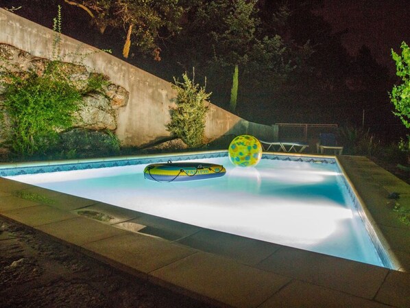 Une piscine avec un radeau flottant et un ballon.