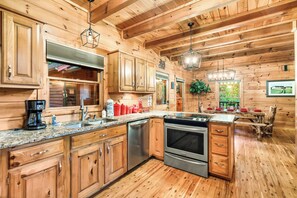 A wooden cabin interior with a kitchen featuring granite countertops, stainless steel appliances, and wooden cabinetry.