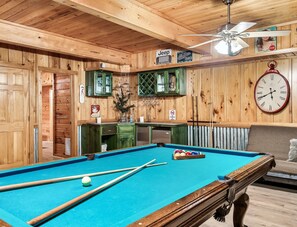 A pool table with cues and balls, a clock, and a smoking sign in a wooden room with cabinets and a ceiling fan. - Spacious Family Cabin | 5 mi to National Park | Hot Tub | Arcade | Pool Table (Townsend)