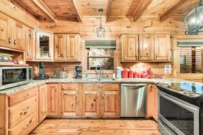 Cocina de estilo cabaña de madera con una isla central, electrodomésticos de acero inoxidable y vistas al exterior.