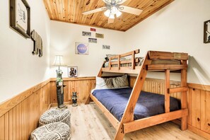 A bunk bed room with wooden walls, a ceiling fan, and various wall decorations including license plates and a NASA logo. - Spacious Family Cabin | 5 mi to National Park | Hot Tub | Arcade | Pool Table (Townsend)