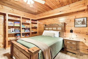 Un dormitorio tipo cabaña de madera con una cama, estanterías con juegos de mesa y un cartel que dice 'EXPLORE' en la pared.