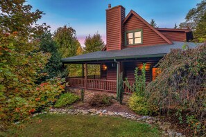 A log cabin with a porch, stone pathway, and surrounding vegetation. - Spacious Family Cabin | 5 mi to National Park | Hot Tub | Arcade | Pool Table (Townsend)