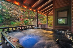 A hot tub with a wooden deck and a view of autumn foliage. - Spacious Family Cabin | 5 mi to National Park | Hot Tub | Arcade | Pool Access (Townsend)