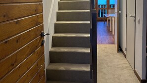 A carpeted staircase with a wooden panel wall on the left and a door on the right.
