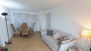A living room with a sofa, chairs, a dining table, and a lamp. - Appartement 2 Chambres Séparées Denviron 60m2 Anglet-plages (Anglet)