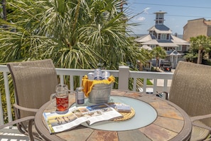 Relax in a serene outdoor setting surrounded by lush greenery and enjoy a refreshing drink at a round table.