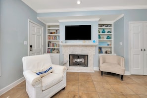 Cozy living room with a fireplace, flat-screen TV, and bookshelf.