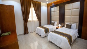 Une chambre d’hôtel avec deux lits, des boiseries, une table de chevet et une fenêtre avec des rideaux.