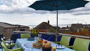 A table set outdoors with a tablecloth, chairs, a table lamp, and a view of the sea. - 4 bedroom accommodation in Harwich (Harwich)
