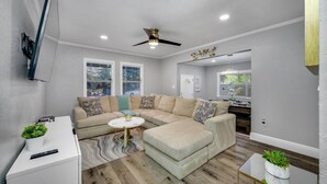 Una sala de estar moderna con un sofá modular, una mesa de centro redonda y un ventilador de techo.