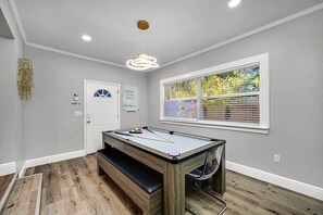 A pool table with a bench, a door, a window with blinds, and a ceiling light fixture. - Heated Pool & Spa, Sleeps 8, South Tampa | 5 Min to MacDill AFB (Tampa)