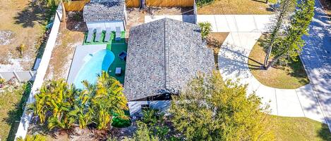 Une propriété résidentielle dotée d’une piscine, d’une cour arrière clôturée et d’une allée pavée.