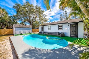 Una propiedad residencial con piscina, un patio cubierto y una pequeña casa con puerta y ventanas.