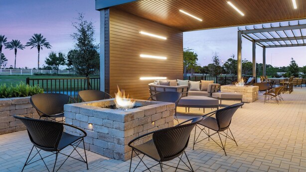 Un patio al aire libre con un brasero, asientos y una zona cubierta con iluminación.