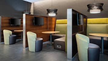 A modern interior with seating areas, tables, and a flat-screen TV mounted on a wooden wall.