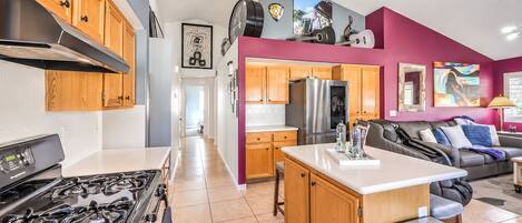A modern kitchen with a stove, refrigerator, and wooden cabinets.