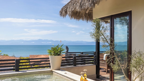 Ein Balkon mit Meerblick, einer Whirlwanne und Blumentöpfen.