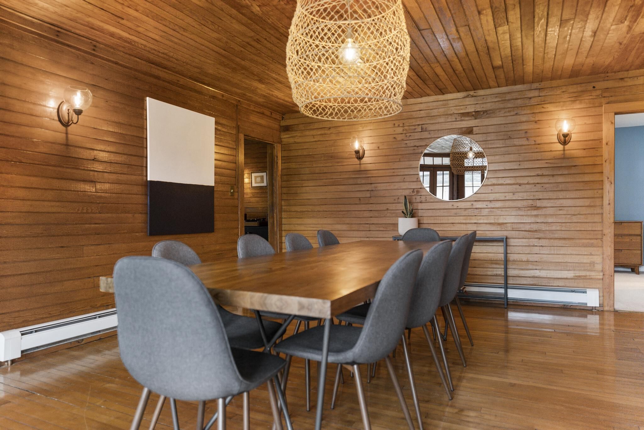 A modern meeting room with a wooden ceiling, a large table, and grey chairs.