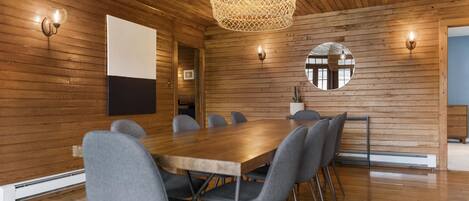 A modern meeting room with a wooden ceiling, a large table, and grey chairs.