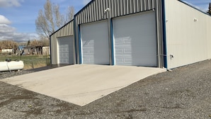 A large industrial building with two garage doors and a paved loading dock.