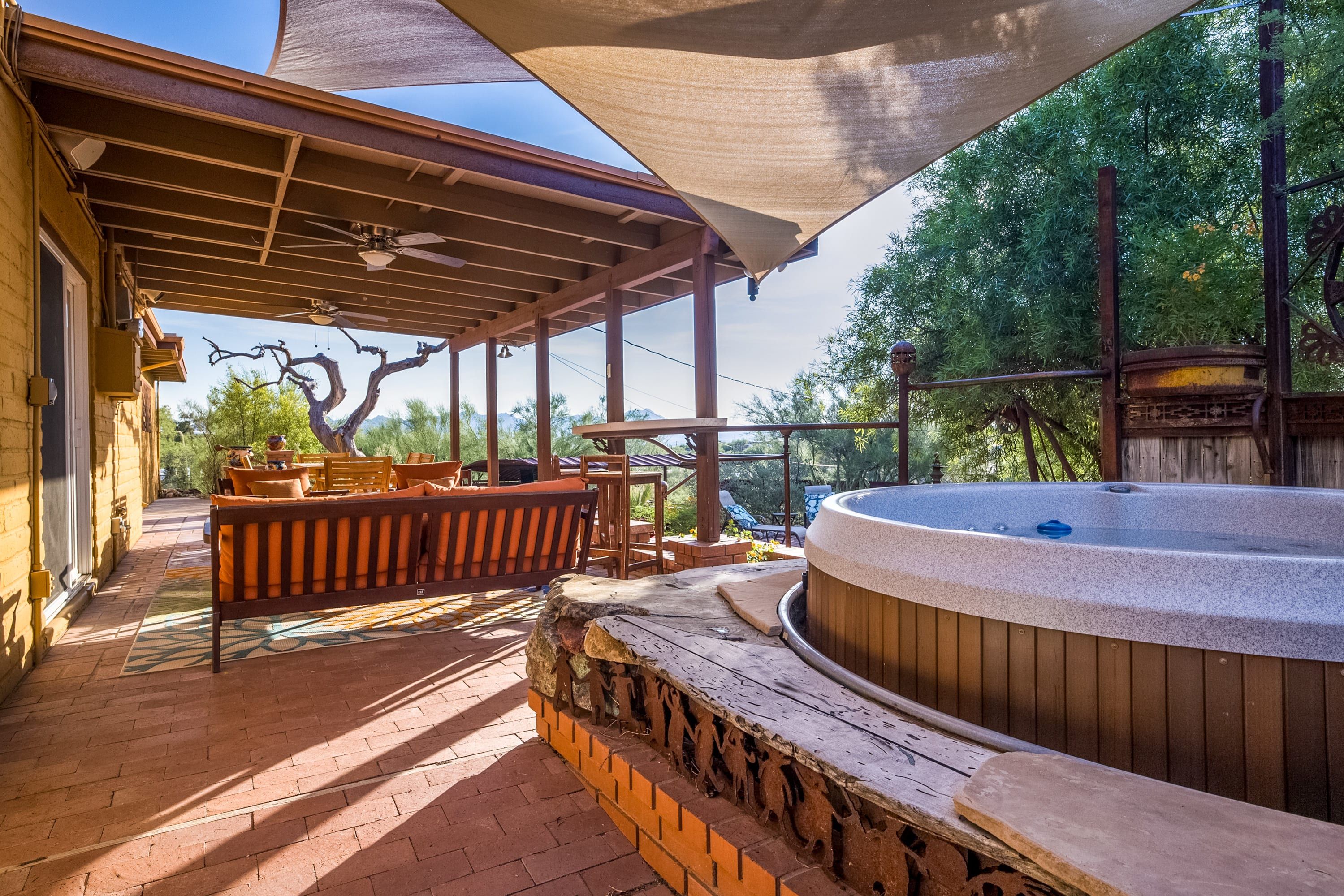 A covered outdoor area with a hot tub, wooden benches, and a patio table.