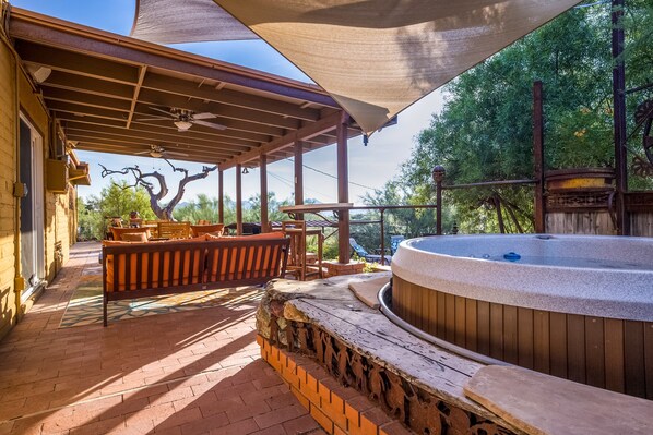 Un espace extérieur abrité comprenant un jacuzzi, des bancs en bois et une table de patio.