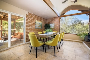 A dining area with a brick wall, yellow chairs, and a wooden table.