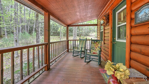 A wooden cabin with a porch, two rocking chairs, and a welcome sign. - Cross Creek Ranch located near Lake Watauga and Mountain City (Mountain City)