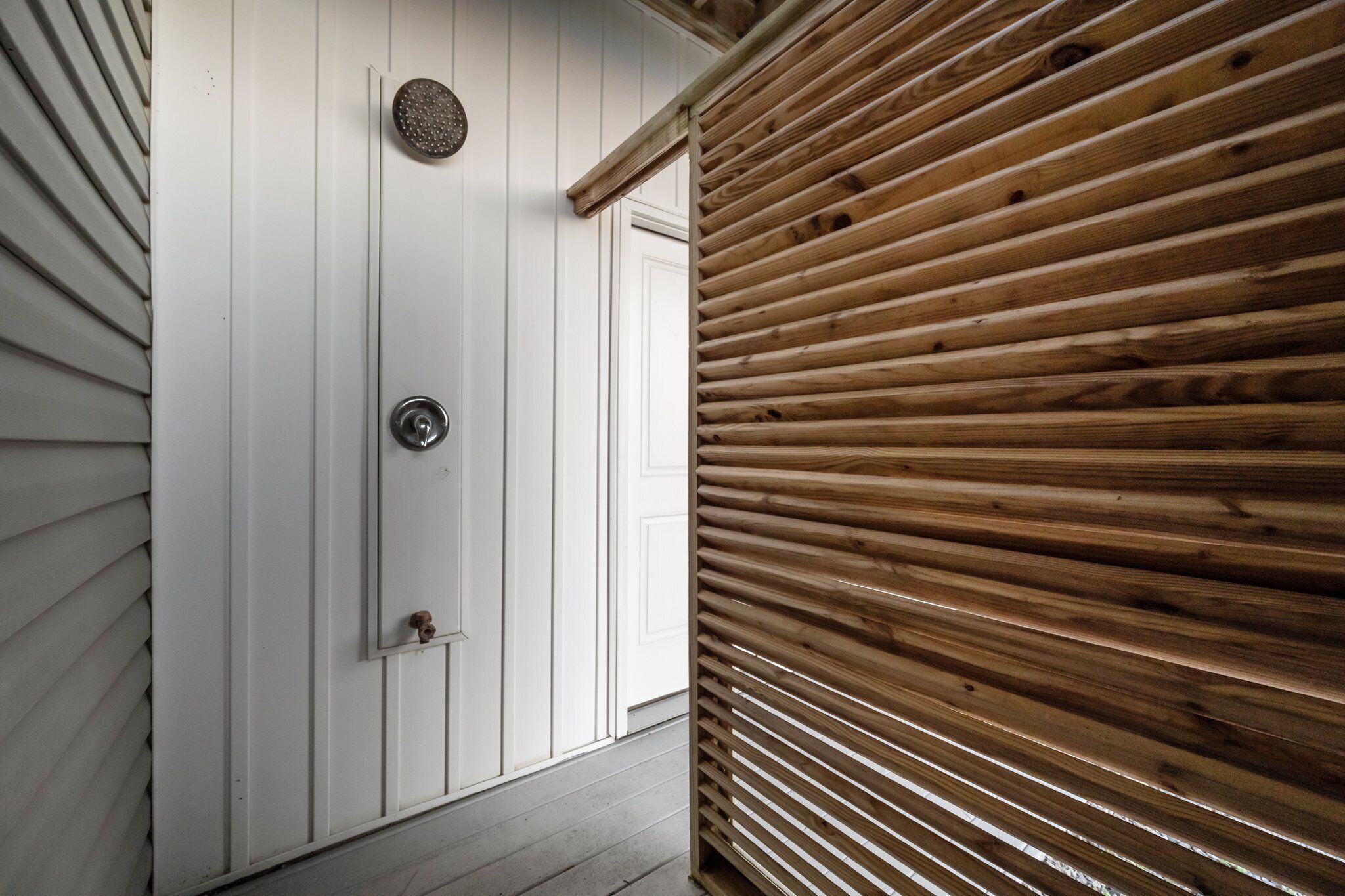 A wooden door with a metal handle and a round, textured metal plate above it.