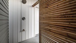 Une porte en bois, dotée d’une poignée en métal et d’une plaque métallique ronde et texturée au-dessus.