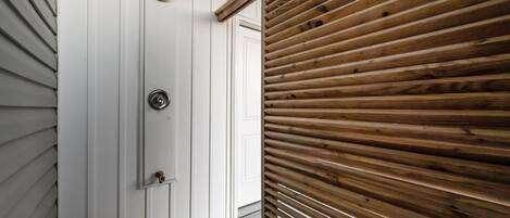 A wooden door with a metal handle and a round, textured metal plate above it.