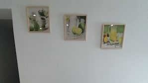 Une table de salle à manger ronde, accompagnée de quatre chaises, un plancher en bois et trois tableaux encadrés accrochés au mur.