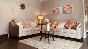 A living room with a sofa, a coffee table, a lamp, and two abstract paintings on the wall.